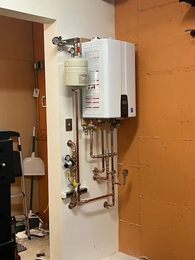 Plumbing technician inspecting water heater connections in Winslow